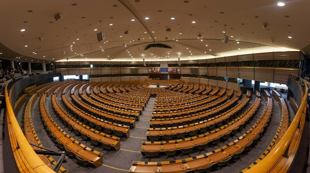 Hémicycle européen aux rangées de pupitres en bois, vu depuis les tribunes
